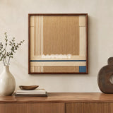 A Collected Morning cream, toasted sand, and indigo yarn wall art displayed above a wood credenza with neutral decorative objects.