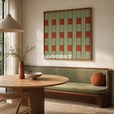 A Wrapped Afternoon moss green and terracotta geometric yarn wall art displayed above a green banquette in a sunlit dining nook.