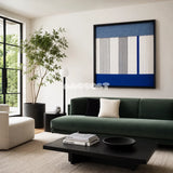 Absolute Zero hazy blue white gray and cobalt textile wall art displayed above a deep green sofa in a bright contemporary living room.
