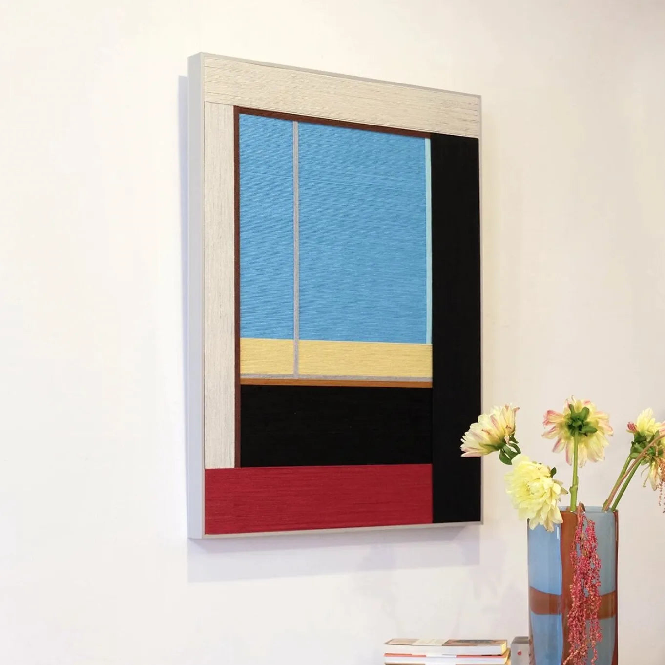 After the Beach Walk wall art styled on a table with lamp and books to showcase its bold coastal-stripe design