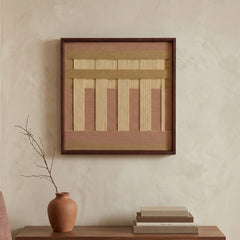 A diptych set of square hand-woven wool wall art in black frames, featuring minimalist black and cream geometric abstract patterns with sage green accents, hanging above a dark wood console.