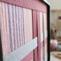 Macro shot of the Bloom Forecast tapestry showcasing the contrast between the thick mauve wool blocks and the fine striped lavender yarn.