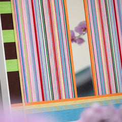 Blooming Flowers wool yarn art resting on an outdoor stone bench, highlighting its delicate pastel stripes against a natural stone backdrop.