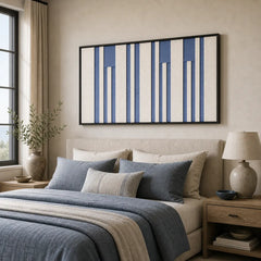 Large rectangular framed wool tapestry hanging elegantly above a neatly styled bed with matching blue bedding in a cozy room.