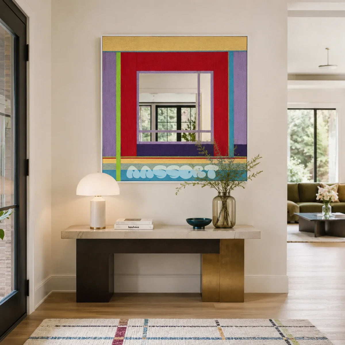 Bohemian Reverie red, lavender, yellow, green, and turquoise yarn-framed mirror displayed above a console table in a bright entryway.