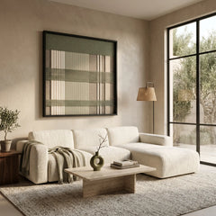 Beautiful framed hand-woven textile wall art styled elegantly above a light beige sectional sofa in a bright, modern living room.