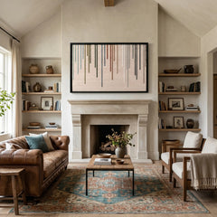 Beautiful colorful framed wall art styled above a traditional fireplace mantel in a grand living room with vaulted ceilings and cozy leather furniture.