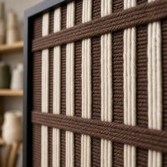 Detailed macro close-up of the Cocoa Cadence hand-woven wool tapestry highlighting the thick brown and cream textured yarn and black frame edge.