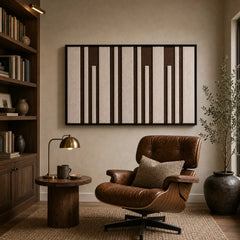 Framed hand-woven wool tapestry styled in a cozy lounge nook positioned above a small table next to a leather armchair.