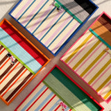 An artistic overhead view of several soft cotton cord wall art pieces overlapping to showcase different colorful striped patterns and textures.