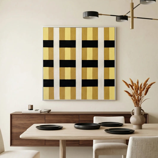 Large square hand-woven wool wall art featuring a bold black, yellow, and cream geometric grid pattern, styled in a minimalist dining room above a walnut sideboard.