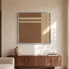 Hand-woven wool wall art with warm brown tones and beige geometric lines hanging above a walnut sideboard in a sunlit room.