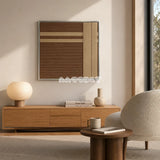 Earth’s Embrace earthy geometric yarn wall art displayed above a wood console beside a curved cream chair in a minimalist living room.