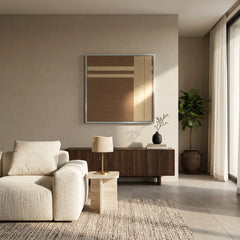 Square hand-woven textile art piece displayed in a bright living space, highlighting the natural brown and tan fiber textures.