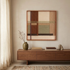 Textured wool wall hanging in a wooden frame styled above a low-profile walnut sideboard, creating a natural and cozy living room aesthetic.