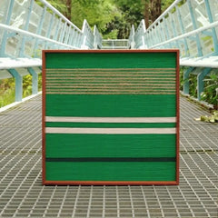 Endless Flow hand-woven wool yarn wall art featuring alternating deep and mint green vertical stripes in a natural wood frame, showcased outdoors