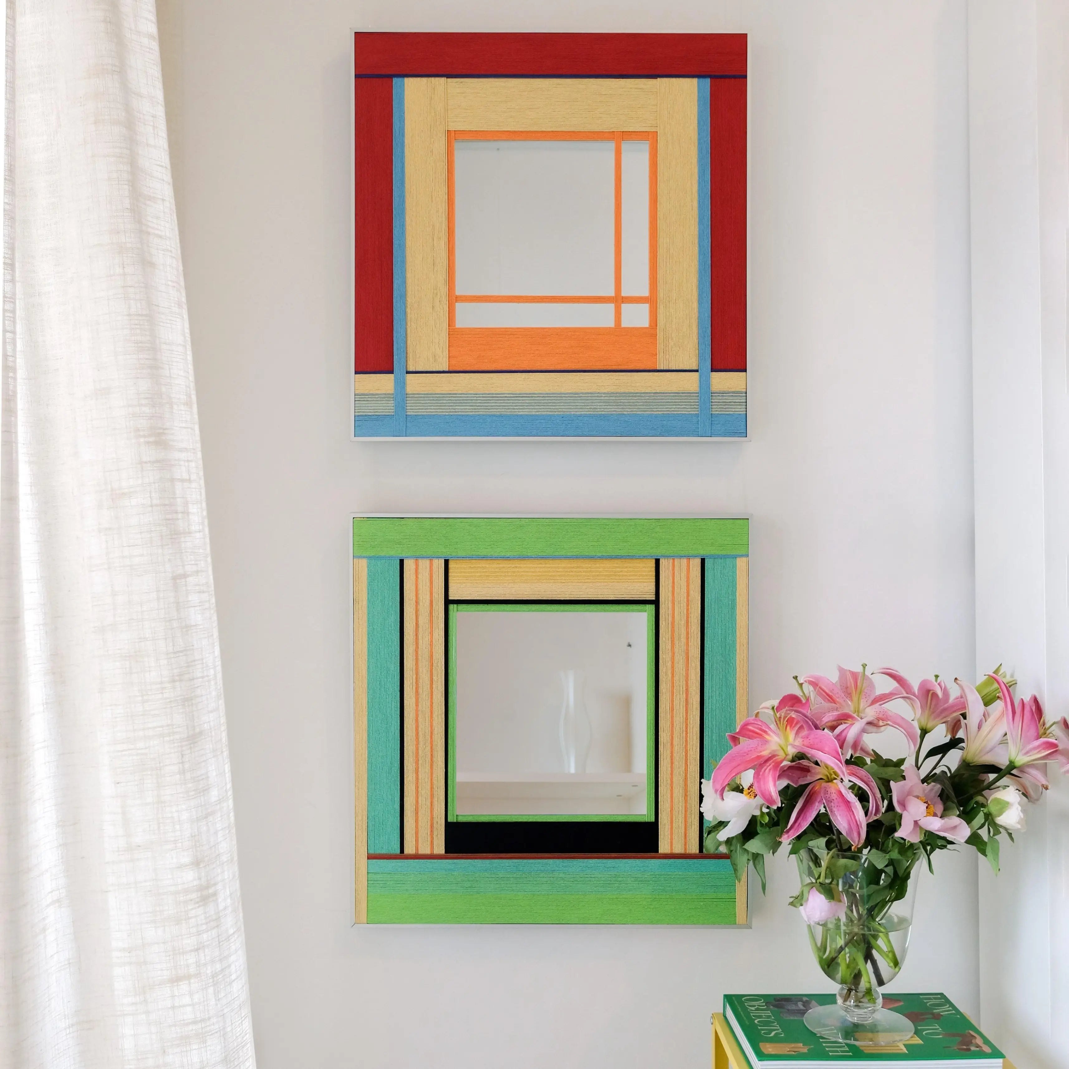 Two variations of the Fields of Blossoms woven mirror collection hanging vertically, comparing the red and green colorway options.