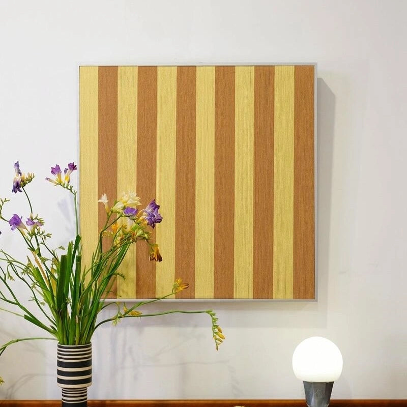 Yellow stripe variant of Hana & Alice yarn art displayed on a console table with lamp and greenery, adding cheerful warmth to interior décor