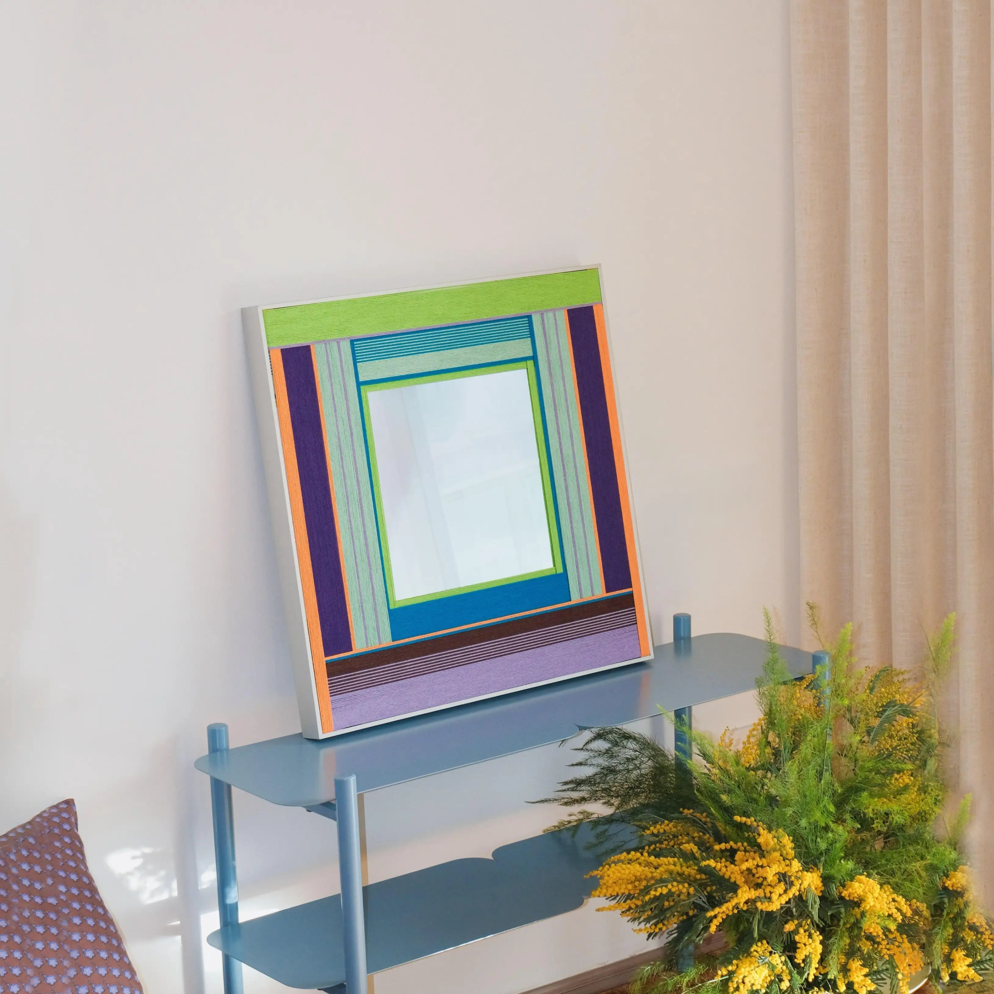 Hand‑held view of Hidden Forest yarn mirror art showing precise stitch details and sturdy wooden frame as it’s being hung.