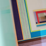 Close‑up of Hidden Forest yarn mirror art border revealing looped soft cotton cord texture and crisp transitions between green, purple, and wood hues.