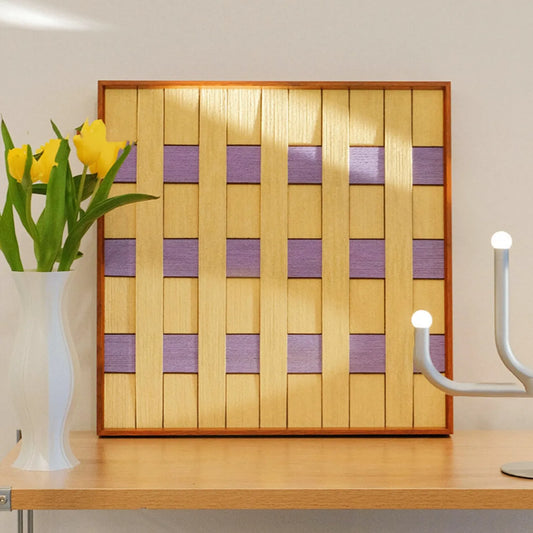 Lover’s Moonlight Violet hand-woven wool yarn wall art with alternating lavender and buttery yellow stripes in a natural wood frame, displayed on a console table with vase and lamp