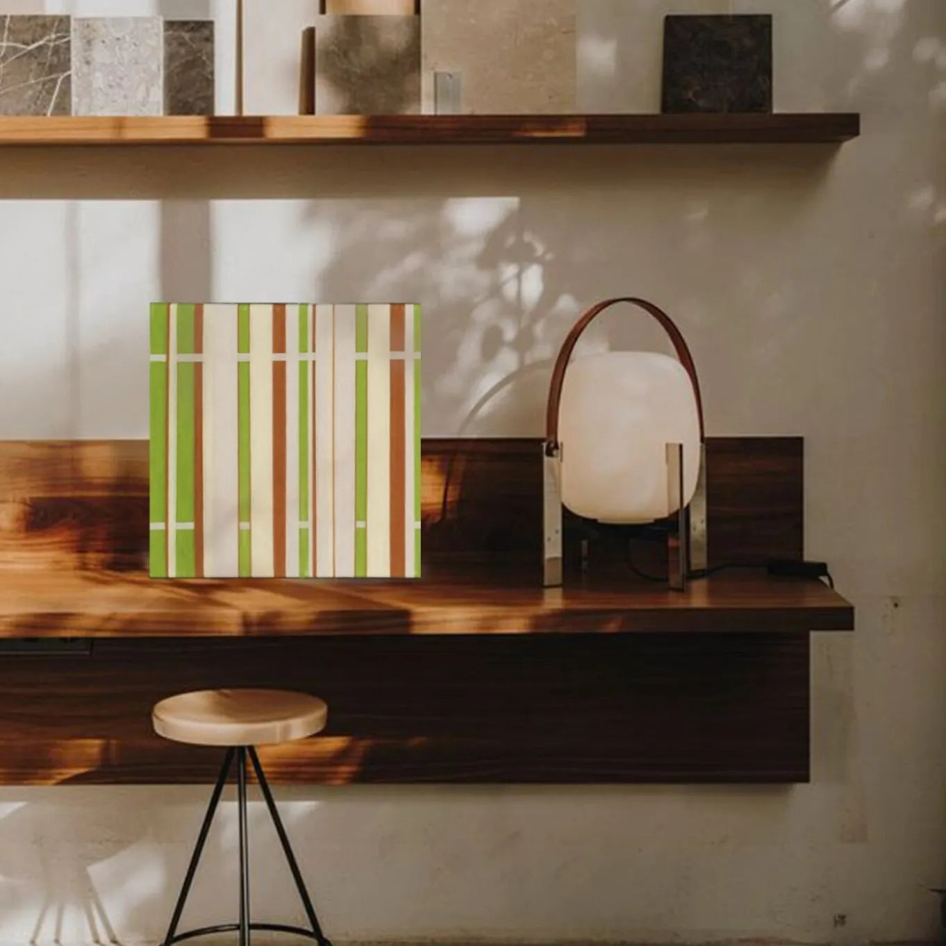 March Tree yarn wall art styled on a desktop shelf alongside books and a vase, showcasing its crisp stripe pattern and compact square format.