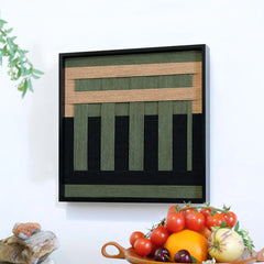 The geometric fiber art hanging on a white wall above a fruit bowl, adding a natural and serene touch to a modern dining space.