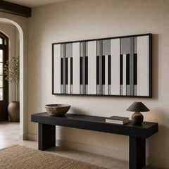 Striking monochrome hand-woven wool tapestry positioned perfectly above a sleek black console table in a bright, modern entryway hallway.