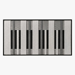 Frontal studio shot of the Monochrome Tempo hand-woven wool tapestry featuring a black, white, and grey piano key geometric pattern in a black frame.