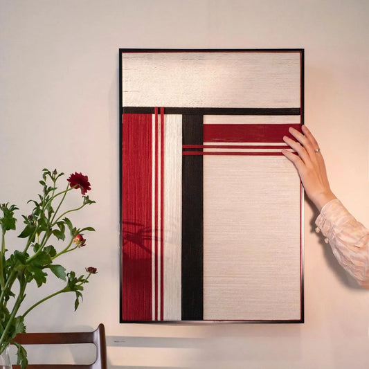 Hand-woven “Napoli” wool yarn wall art with bold red and black vertical stripes on a white panel framed in dark wood for a striking focal point