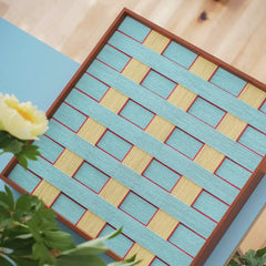 Overhead shot focusing on the symmetrical grid layout of the woven yarn art with equal-sized blue and yellow blocks