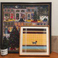 Two Pawsy Puppy yarn wall art pieces mounted side by side on a white gallery wall, showcasing matching puppy motif panels in complementary color schemes.