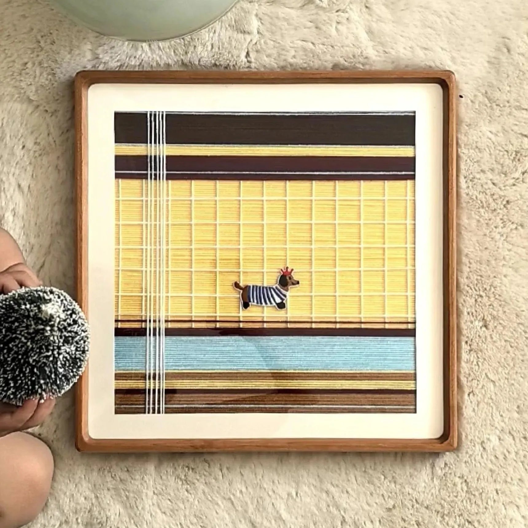 Pawsy Puppy yarn art resting on a stone ledge outdoors, highlighting its durable wool texture and bright grid pattern with puppy silhouette.