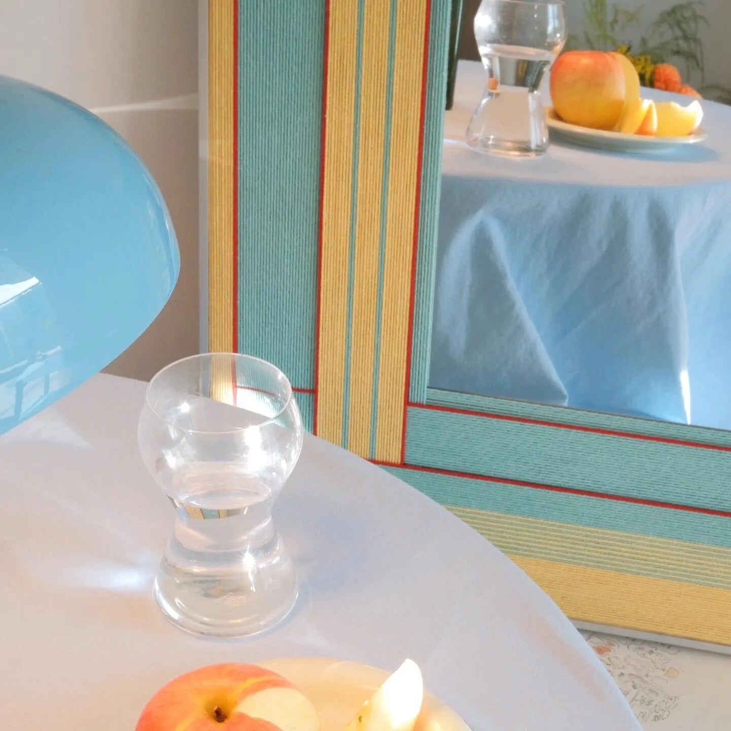 Hand‑held view of Pear Blossom Tree yarn mirror art being mounted on the wall, highlighting its lightweight frame and precise stripe alignment.