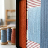 Macro detail of Cold Fire textured textile art highlighting raised rust and light blue yarn over pink and white stripes.