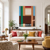Wild RE001 framed textile art with earthy brown, emerald green, sky blue, cream, and red geometric yarn blocks in a modern interior.