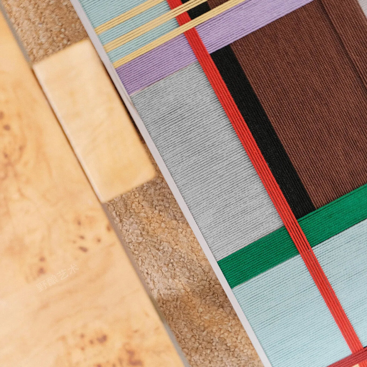 Close-up of City Rhythms RE012 textile art showing intersecting light blue, brown, red, green, and lavender soft cotton cord lines.