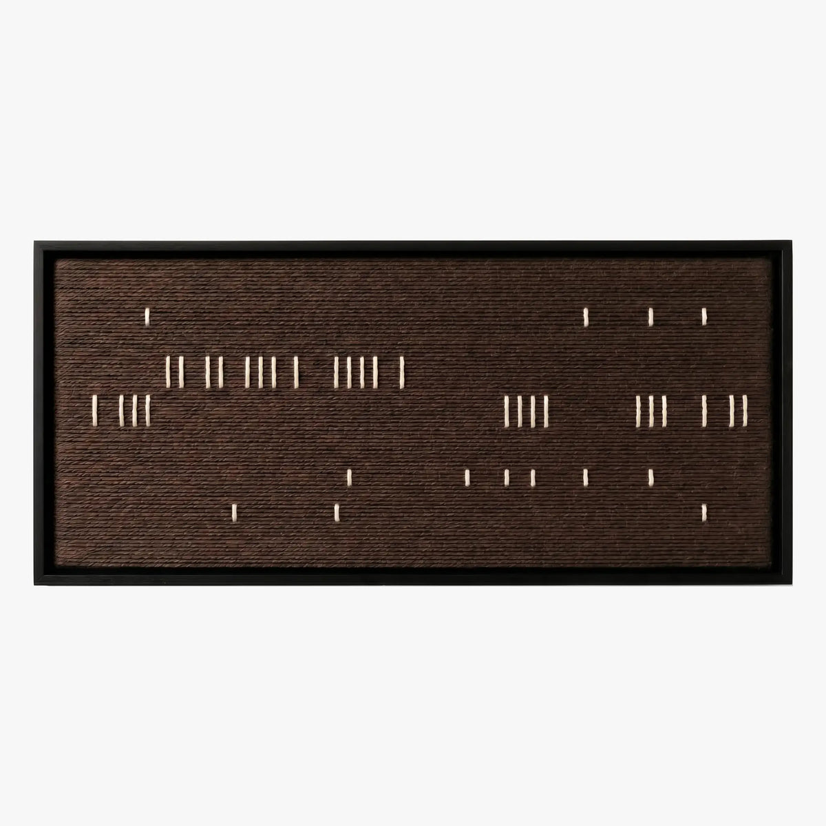Front studio view of Cocoa Whispers textured wall art with scattered white vertical stitches on a dark brown background in a black frame.