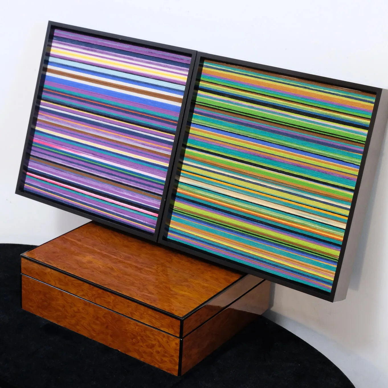 Reconstructing the Future diptych panels placed on stacked wooden boxes, showcasing the coordinated stripe design across both frames.