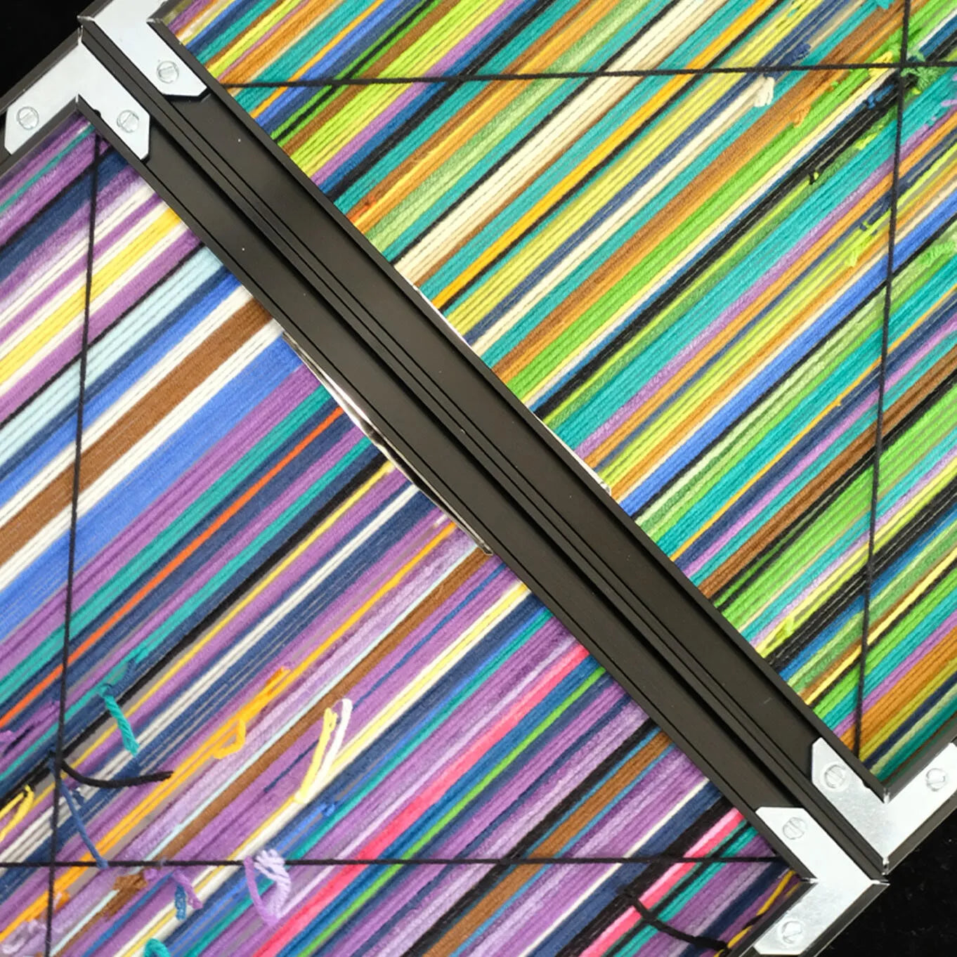 Angled close-up of Reconstructing the Future yarn wall art highlighting vibrant looped wool texture and precise stripe transitions.