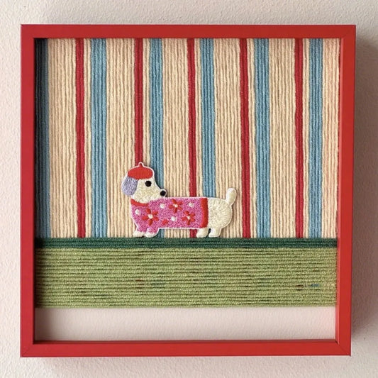 Scarlet Stripe Pup Saunter hand-woven wool yarn wall art with alternating scarlet red, ivory, and sage green vertical stripes, framed in vibrant red wood and displayed on a wooden console table.