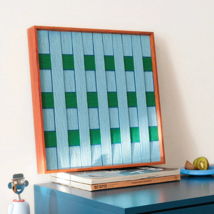 Seine Riverbank yarn wall art styled on a laptop keyboard with matching yarn balls, showcasing precise stripe alignment and compact square design