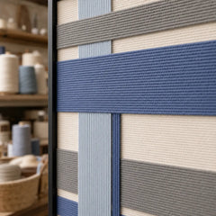Angled close-up showing the black frame edge and dimensional blue and grey hand-woven wool tapestry texture.