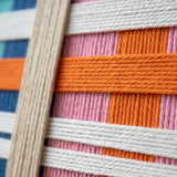 Close-up of Scale of Joy SQ109 showing handmade yarn texture and colorful interwoven geometric patterns.