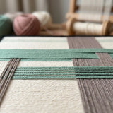 Angled workshop view of Muted Spring SQ115 highlighting dimensional sage green and gray yarn craftsmanship.