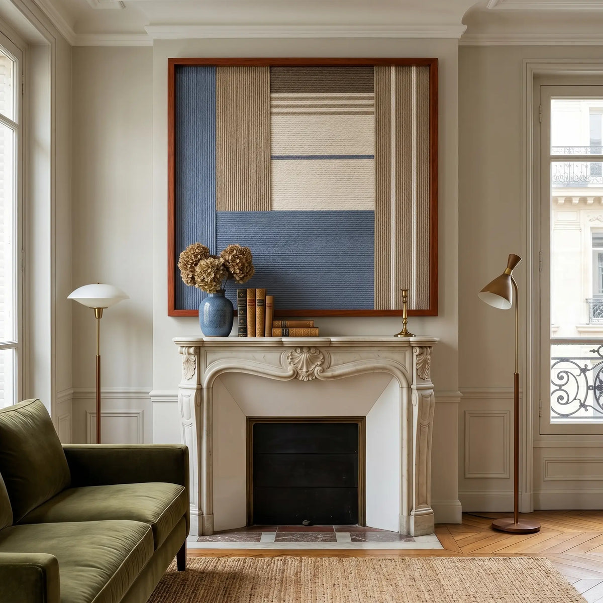 Cerulean Mist SQ130 framed textile artwork displayed above a fireplace in a bright room with an olive green sofa.