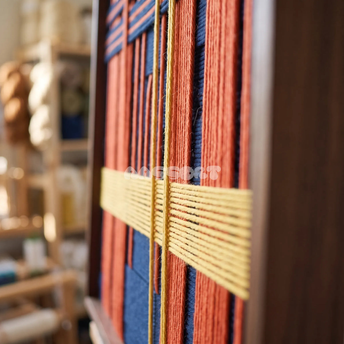Detail of Constructed Mind framed textile wall art, featuring navy cotton cord with terracotta grid bands and a yellow vertical accent.