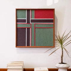 Styled view of the geometric wool wall art above a low console table with books, demonstrating versatile home decor placement options.