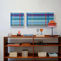 Summer Story yarn wall art displayed on a wooden shelf next to books and ceramics, showcasing the clean stripe pattern and sturdy frame