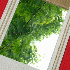 Close-angled view of The Sun Always Rises yarn mirror art highlighting tight looped wool texture on stripe borders and the reflective center catching natural light.